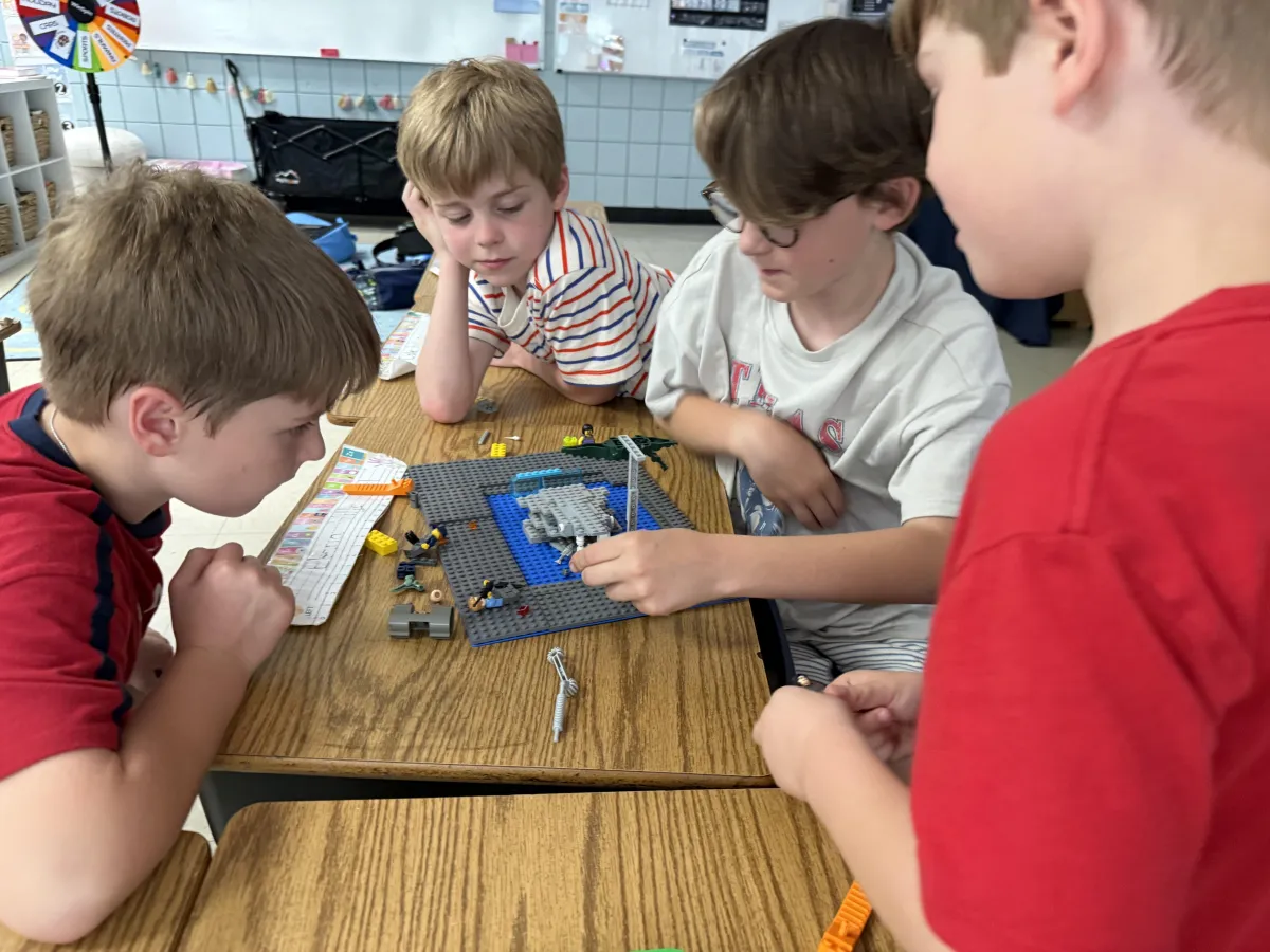 Two children smiling and working together on a collaborative LEGO build