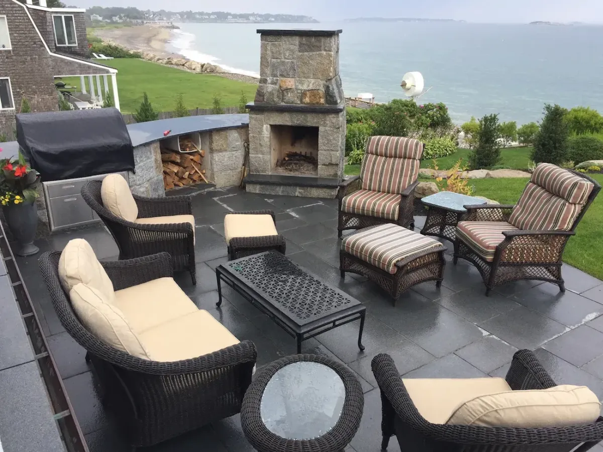 Custom stone outdoor fireplace with bluestone patio and coastal oceanfront seating area in Marblehead, MA by Nash & Brown Masonry.