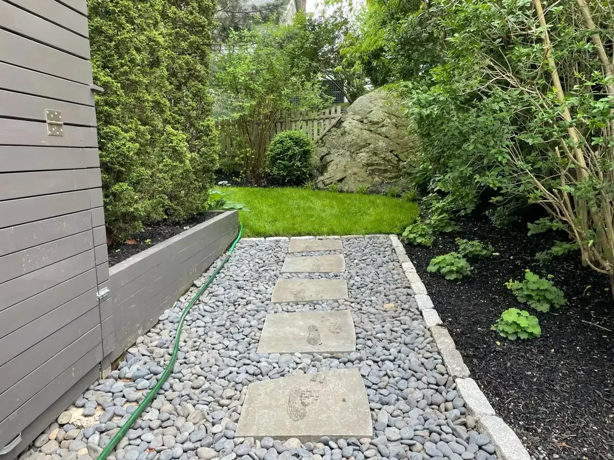 Custom stone stepping path with decorative river rock, granite edging, and professional landscape construction in Marblehead, MA by Nash & Brown Masonry.