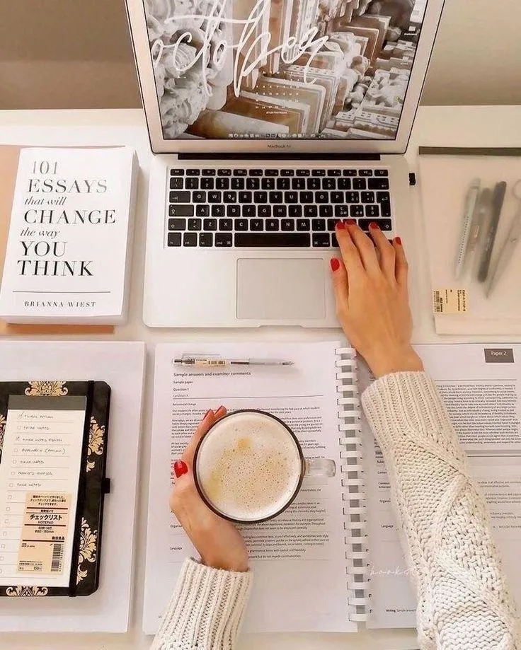 A diverse group of professionals in business attire, gathered around a glass table in a sunlit office, engaged in a lively discussion with notepads and laptops, symbolizing collaboration and premium consulting.