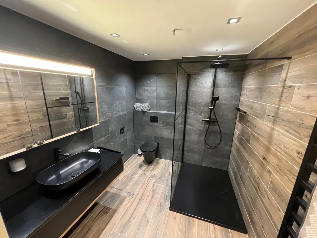 Modernes Badezimmer mit dunklen Fliesen und Dusche