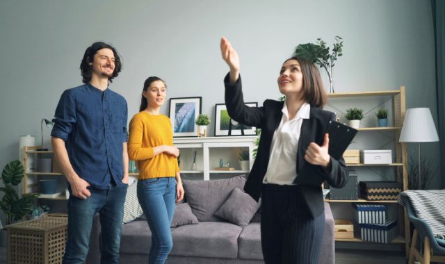 Clients reviewing home building plans with a real estate agent before deciding whether to build or buy an existing home.