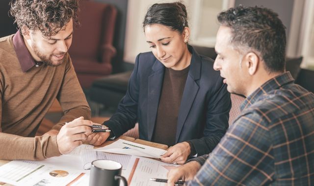 Real estate agent discussing mortgage pre-approval with a home buyer while reviewing property documents before purchasing a home