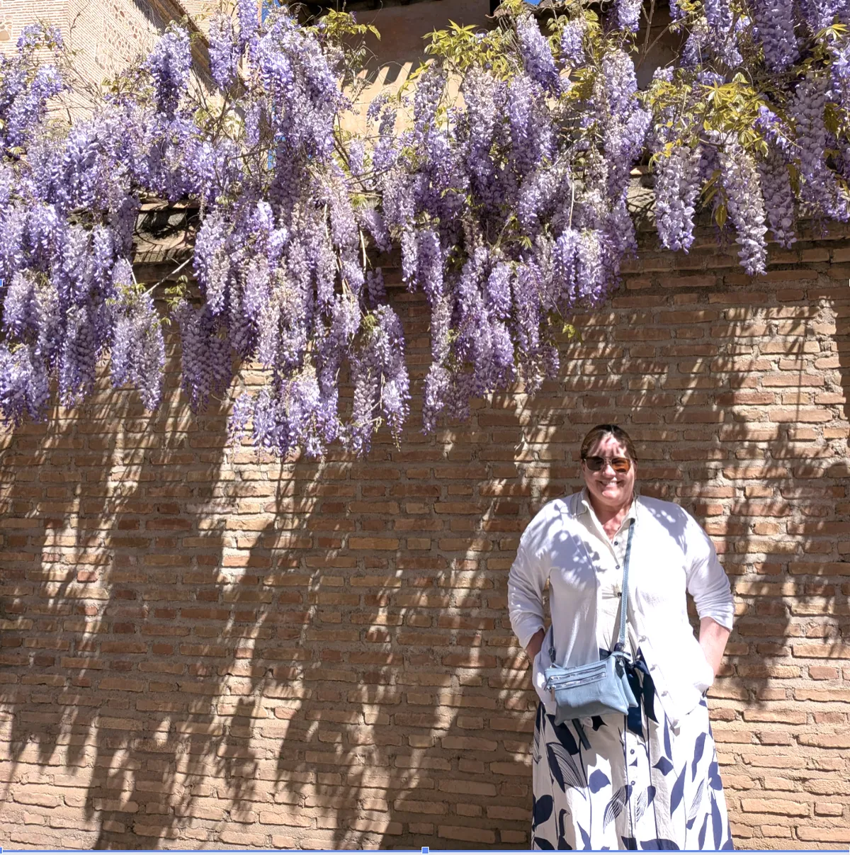 Jenn standing in front of a wall of flowers in Spain