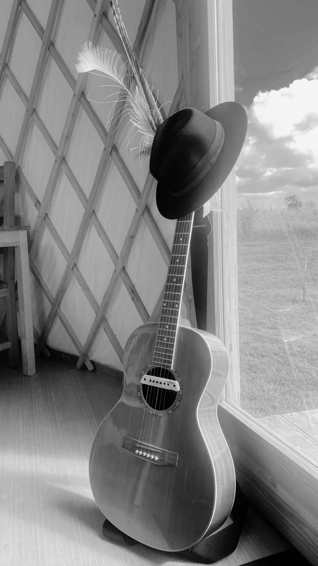 Young woman playing guitar on bed with laptop.