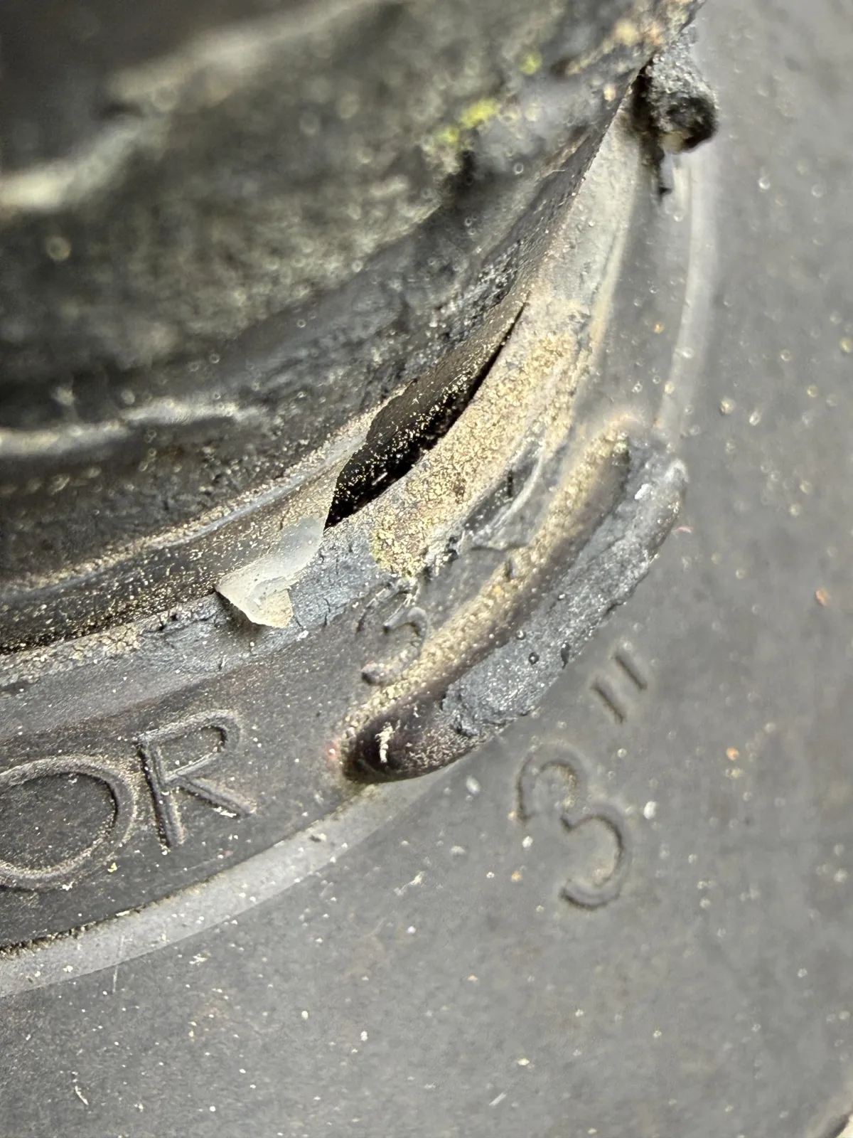 Close-up of a crack in a 3-inch rubber plumbing vent collar on a roof.