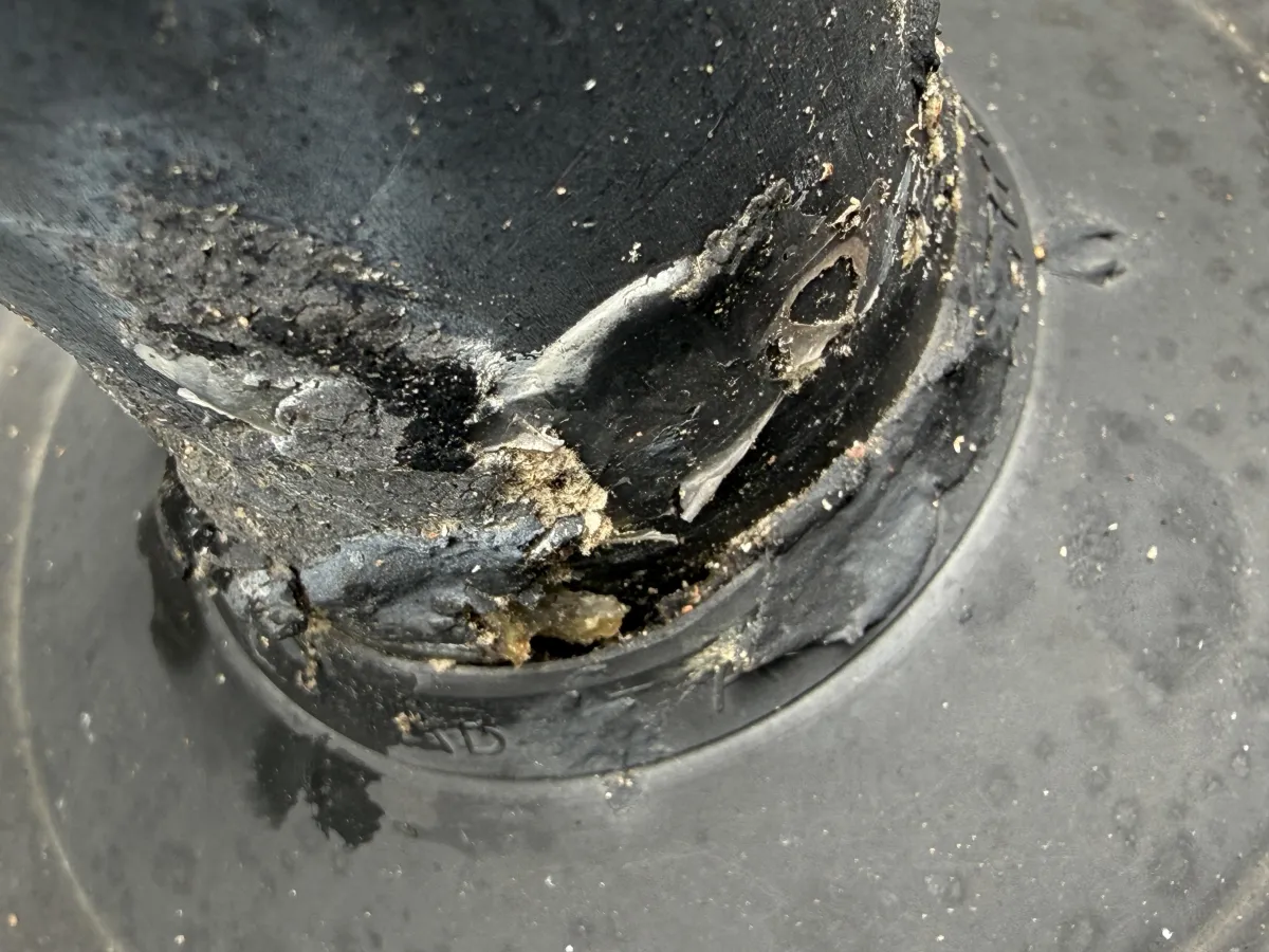 Close-up of a degraded and cracked rubber collar seal on a roof plumbing vent pipe