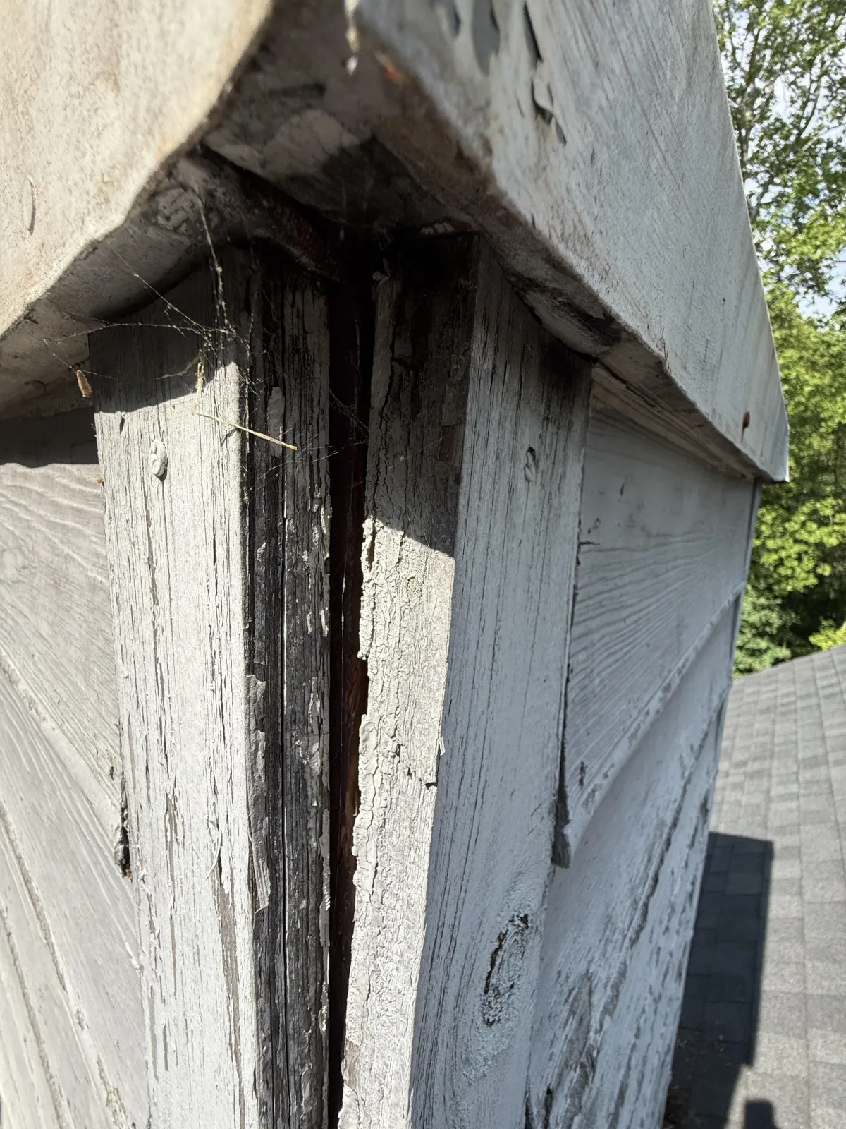 Close-up of a wide gap and separation between weathered wooden corner trim boards on a chimney stack