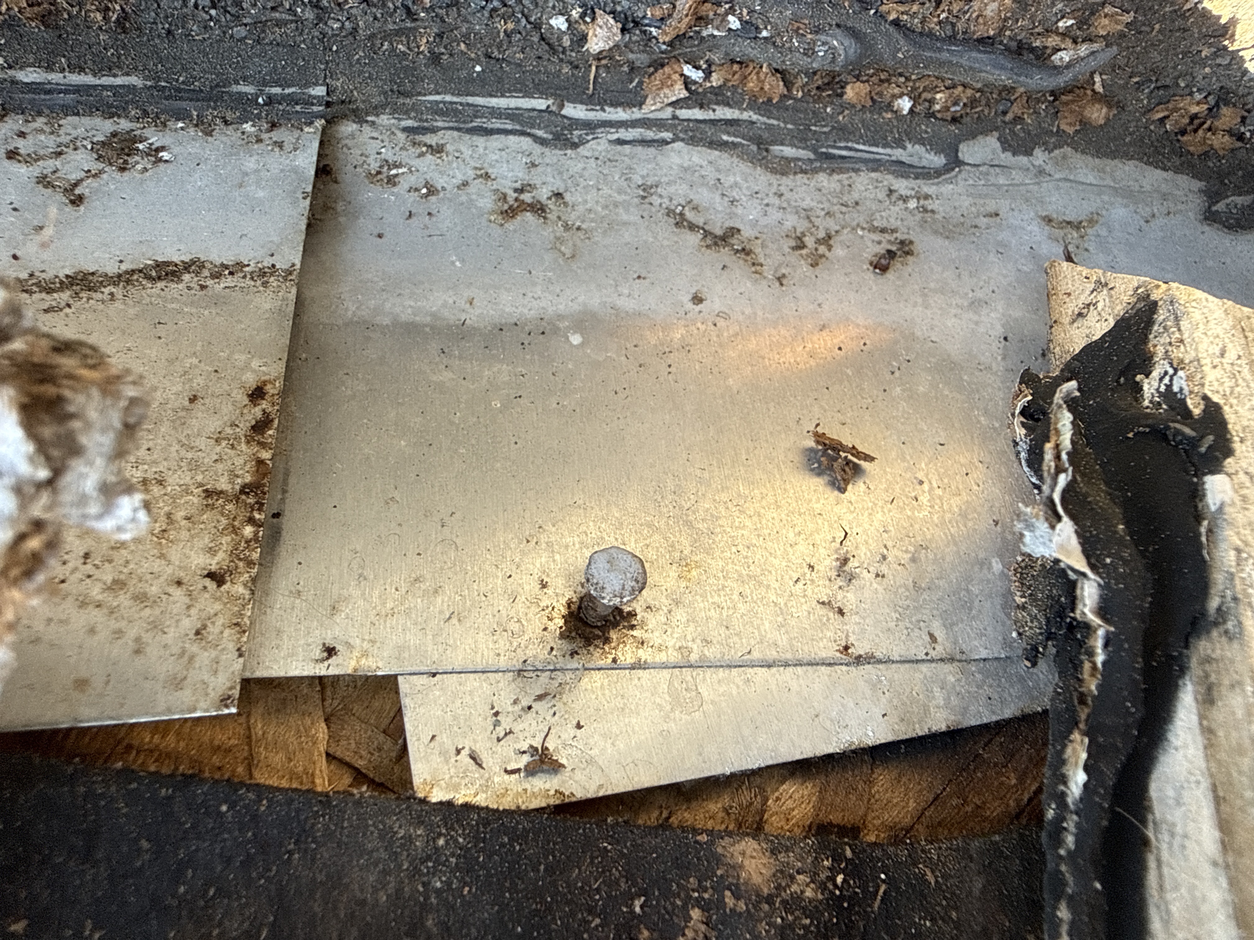 Close-up of damaged, rusted metal step flashing and deteriorated siding panels