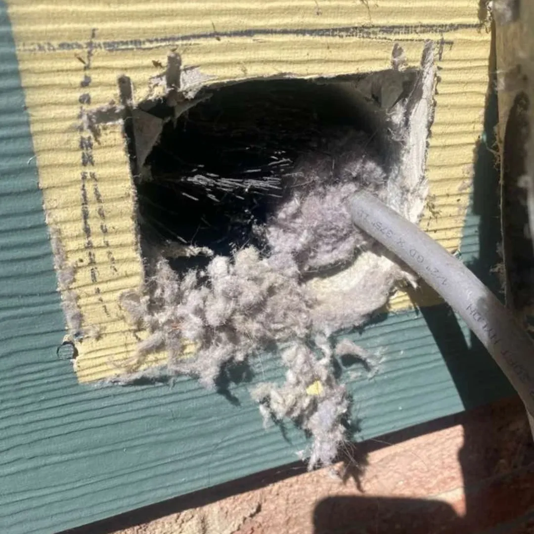 Blocked exterior vent packed with dangerous lint and debris causing a fire hazard.