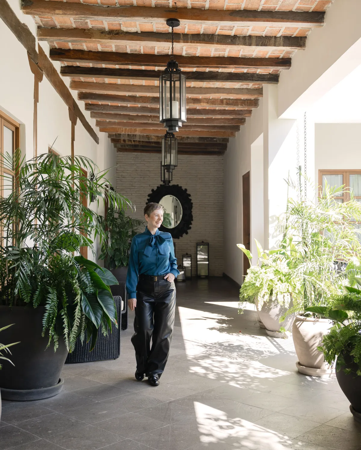 Pamela Dale walking through a plant-filled courtyard in Mexico City