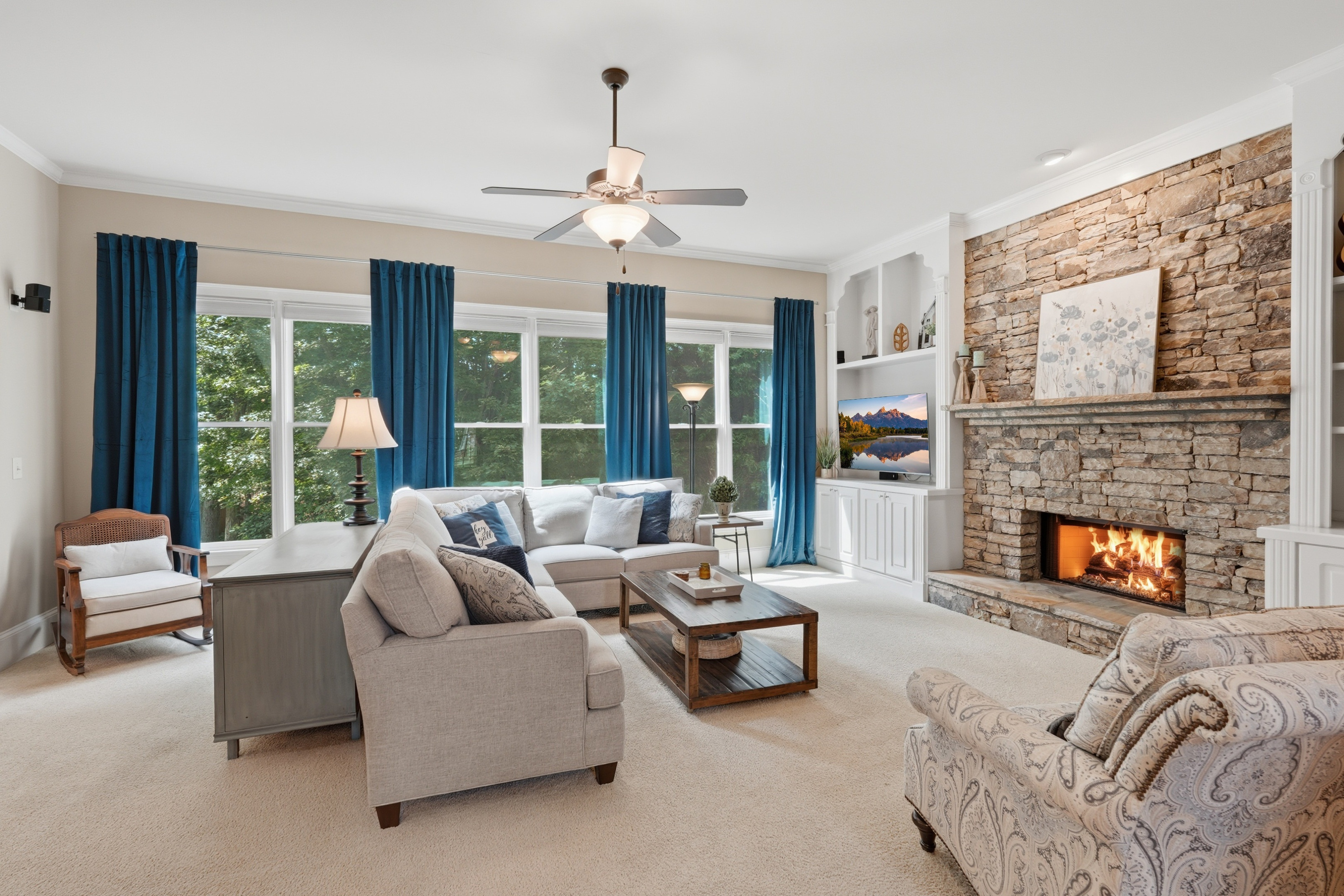 Living room with floor-to-ceiling stacked stone fireplace and large windows at 272 Beechtree Hollow, Sugar Hill, GA.