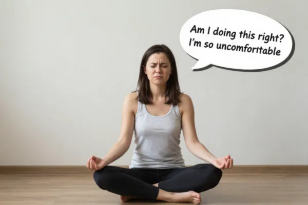 An image of a lady with her legs crossed in a yoga posed, looking grumpy. There is a thought bubble that says "am I doing this right? I feel so uncomfortable"