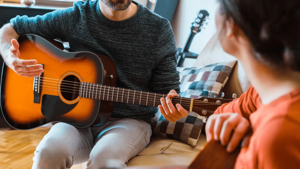 A guitar teacher demonstrating a technique to a student