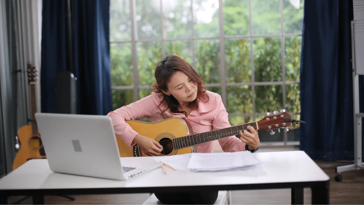 Student practicing her guitar with focus and intention to internalise the material