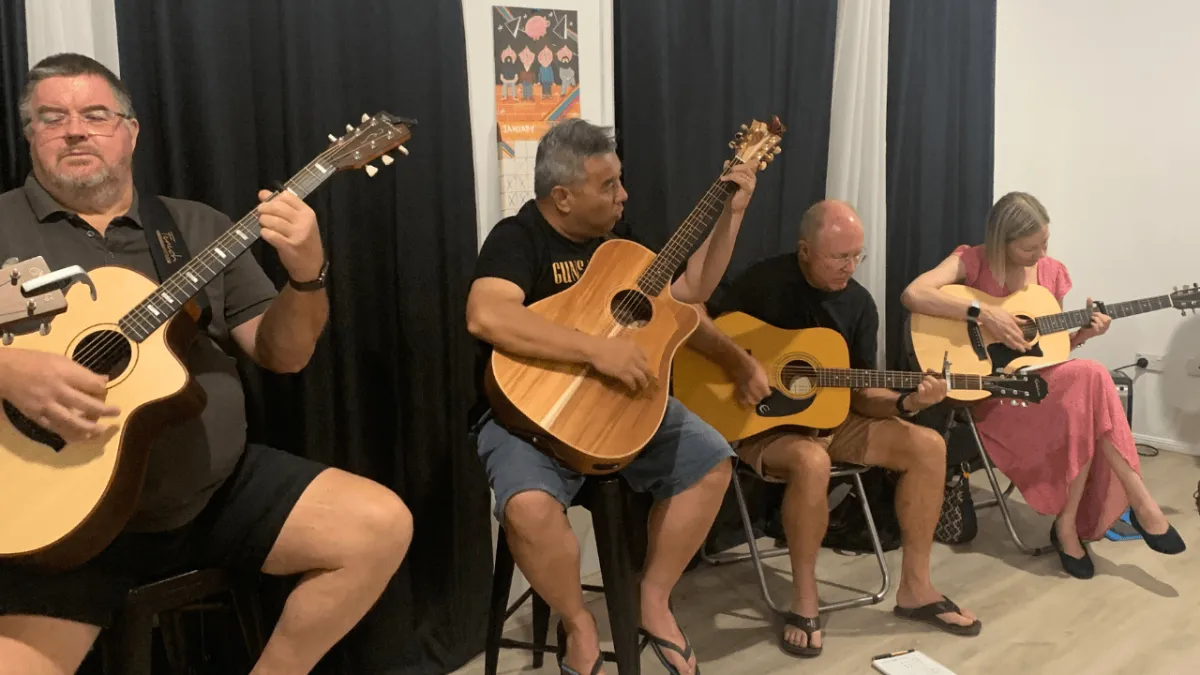 Adult having fun playing songs together in a small group guitar class near me