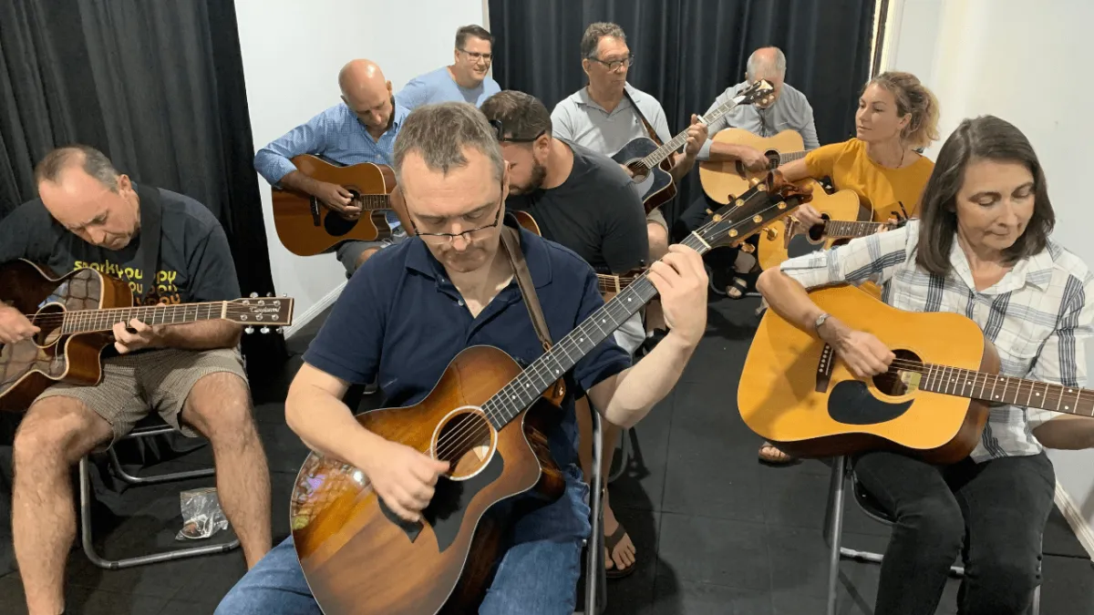 Adult guitar players finally learning to play songs in Carrara