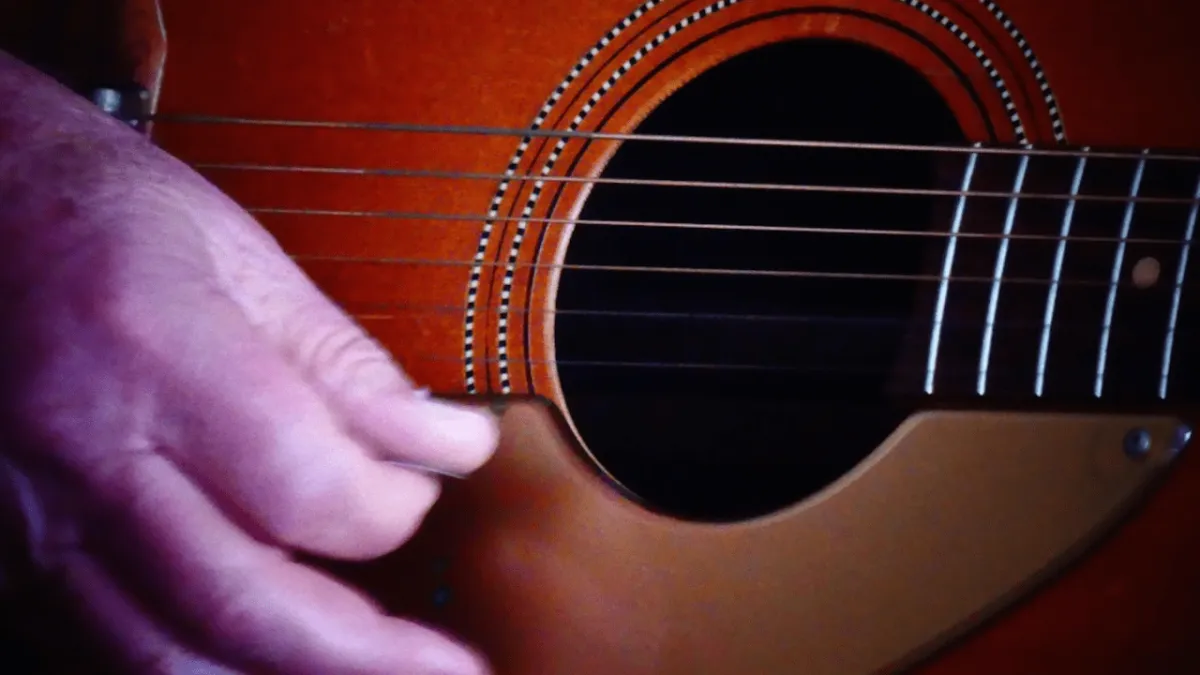 Beginner guitar player practicing strumming technique with acoustic guitar