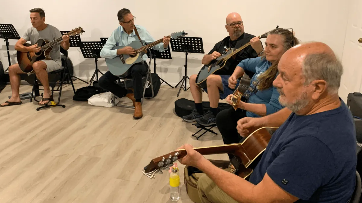 Adult student smiling after learning first guitar song