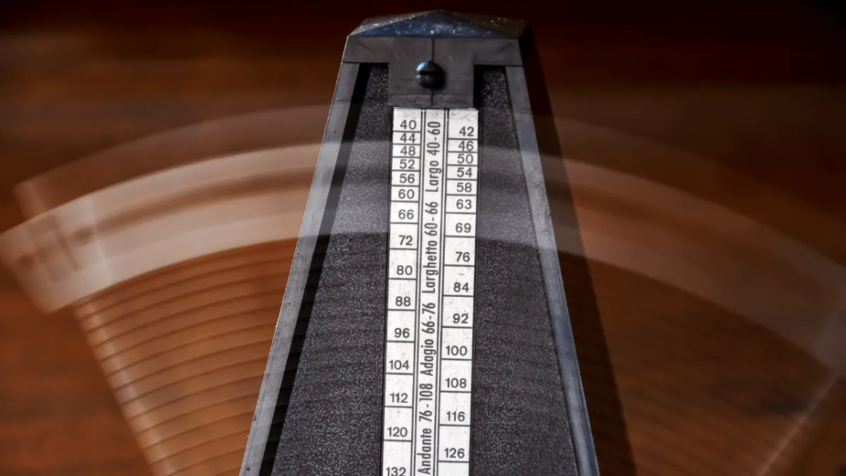 Close-up of metronome and guitar on table to support slow rhythm training.
