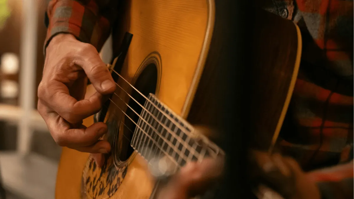 Right strumming hand moving steadily in up-and-down motion over guitar strings.