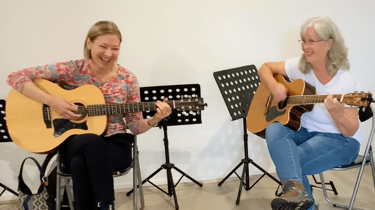 Beginner students learning guitar in a real adult group class in Carrara