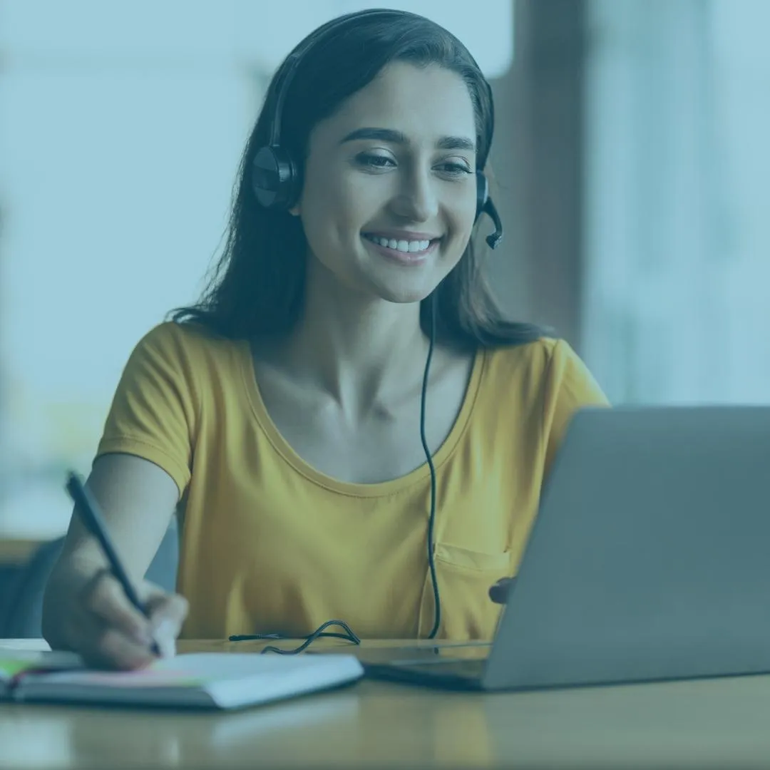 Smiling woman with a headset taking notes during an online training session, representing ADHD-friendly organizer education.