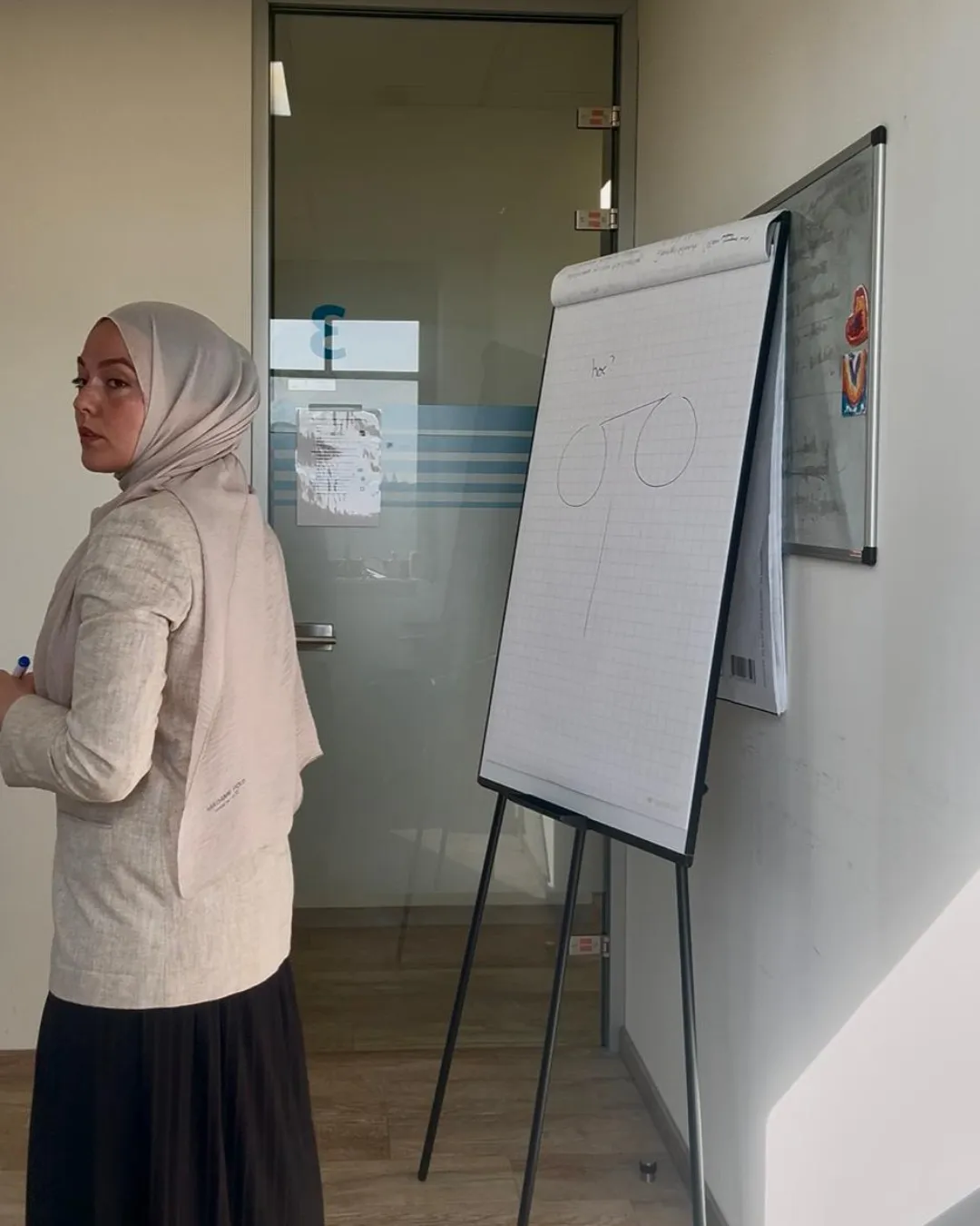 A Turkish woman in her 40s sits at a cozy desk with a laptop, a cup of tea, and a notepad, sunlight streaming through a window, soft feminine decor, calm and inviting atmosphere.
