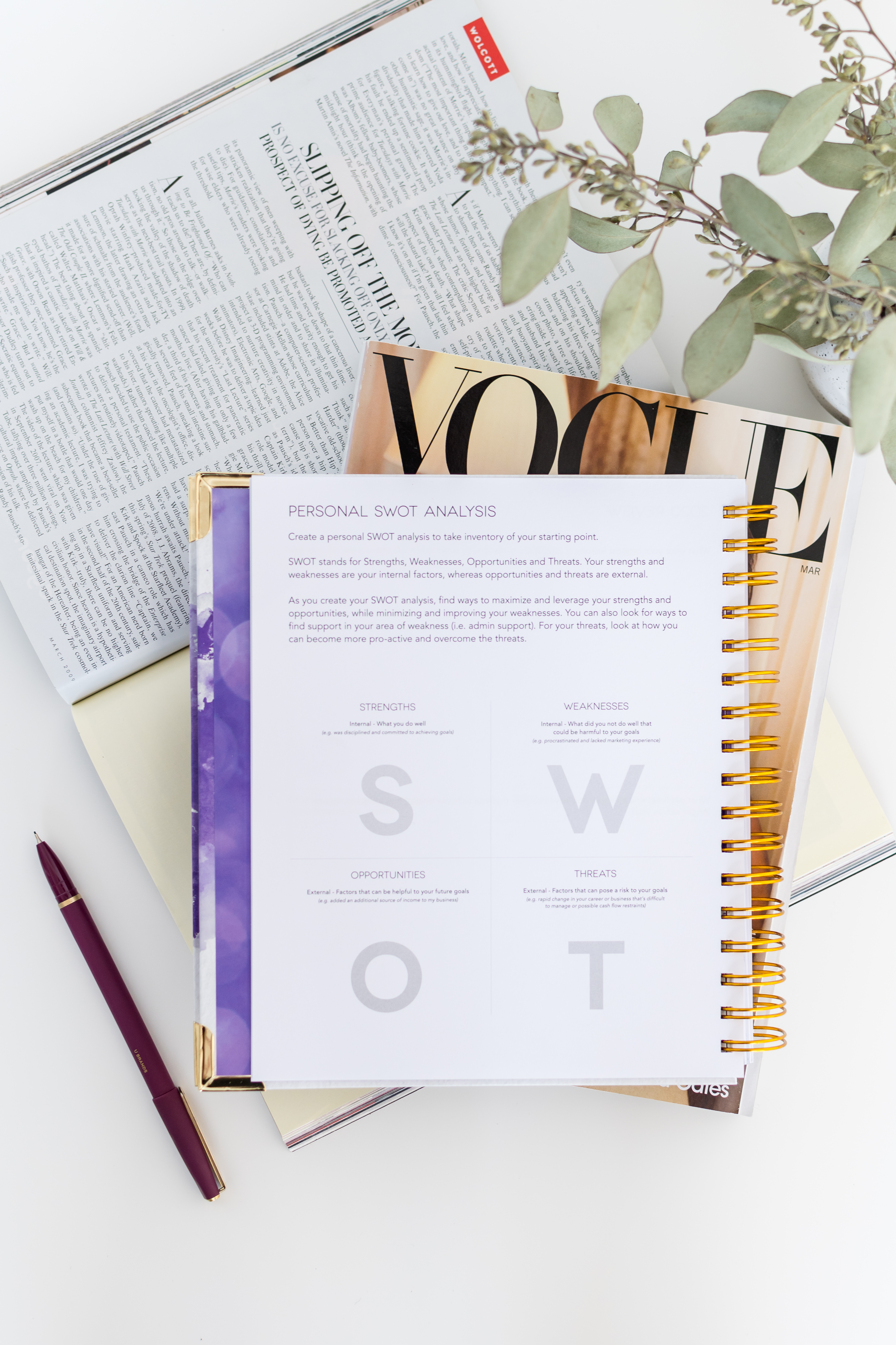Multiple floral and patterned planner covers scattered among pink flowers on a light surface