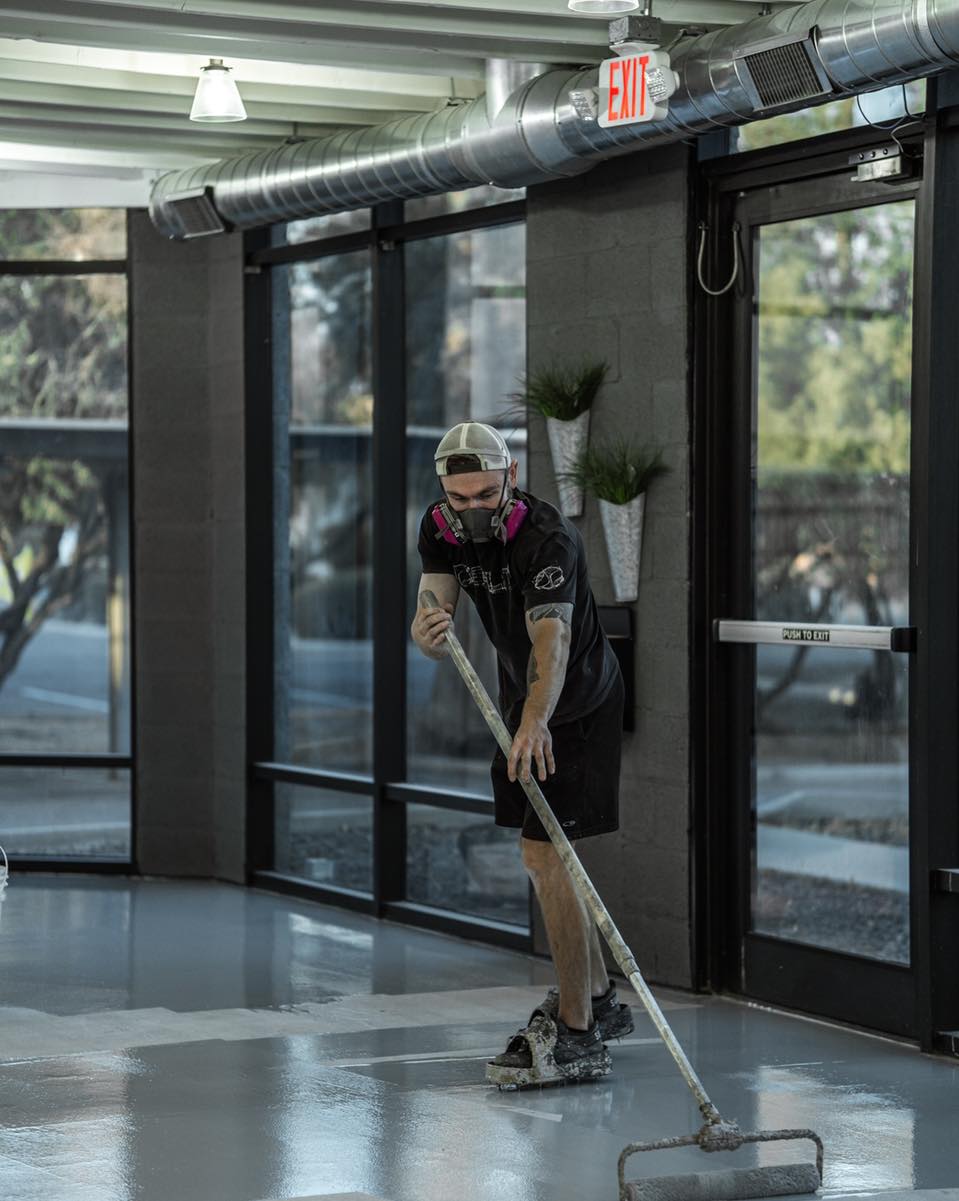 Professional installer rolling out an epoxy coating across a commercial concrete floor during application.
