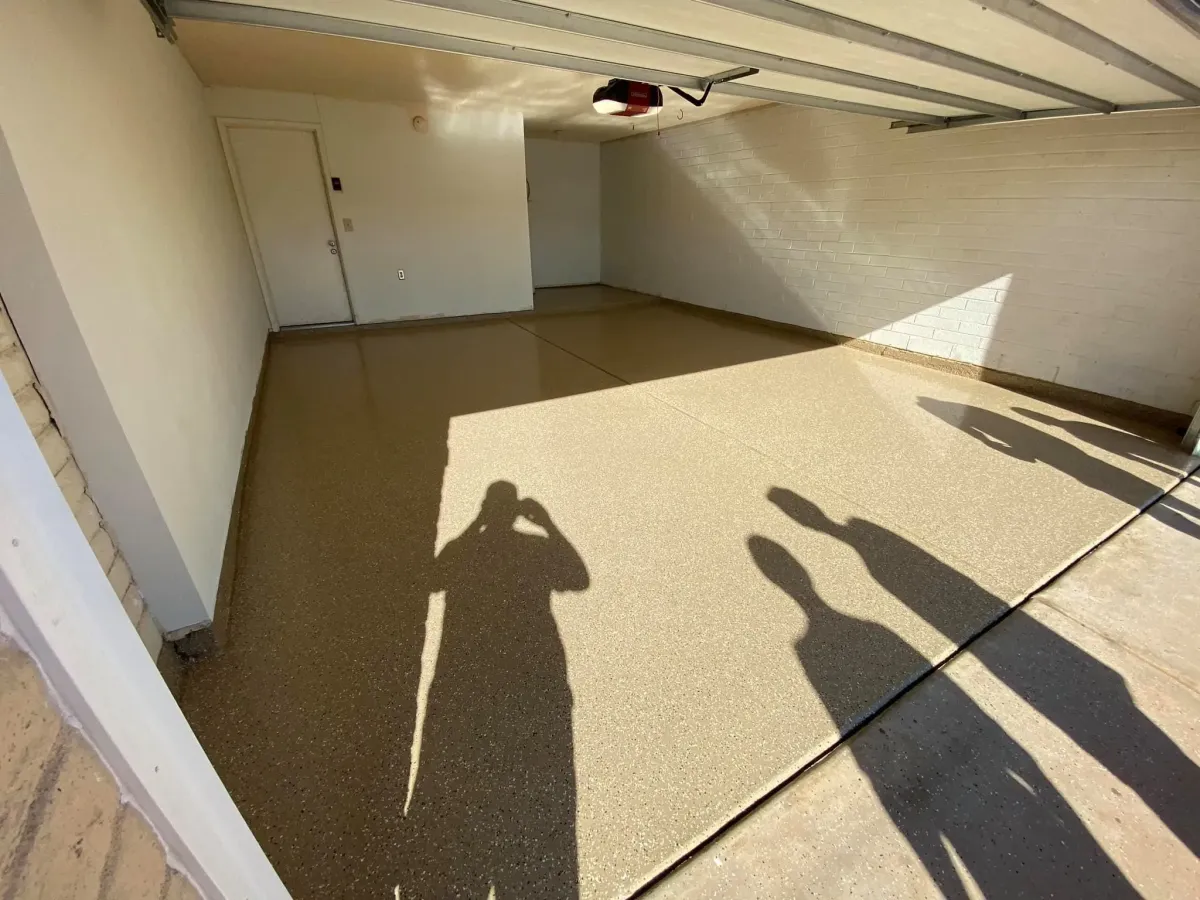 Freshly coated epoxy garage floor reflecting sunlight inside an empty single-car garage.