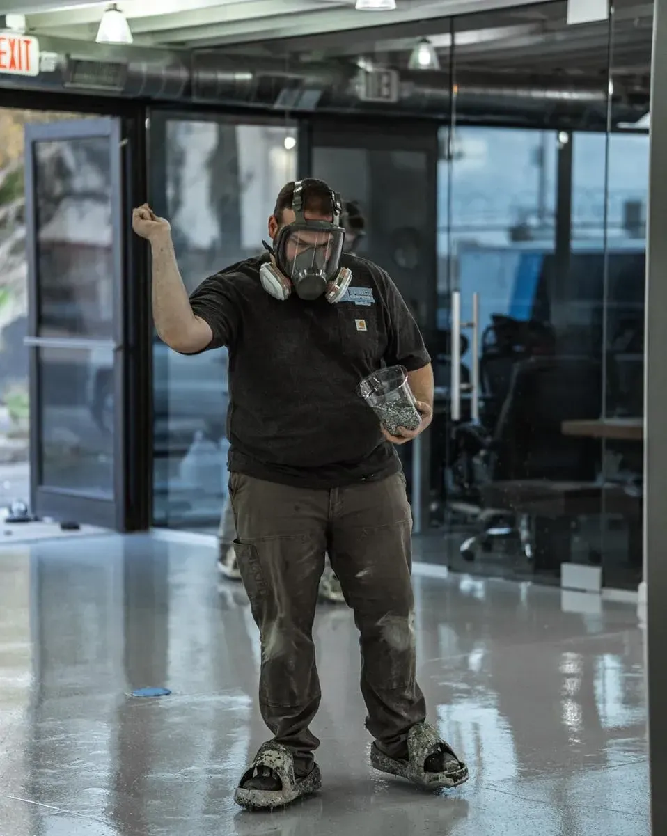 Professional installer broadcasting decorative flakes during an epoxy floor coating inside a commercial space.