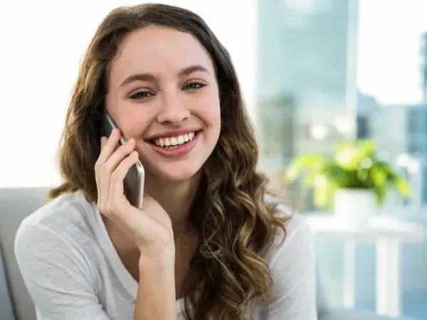 Smiling homeowner on the phone contacting a garage flooring company to request a free estimate.