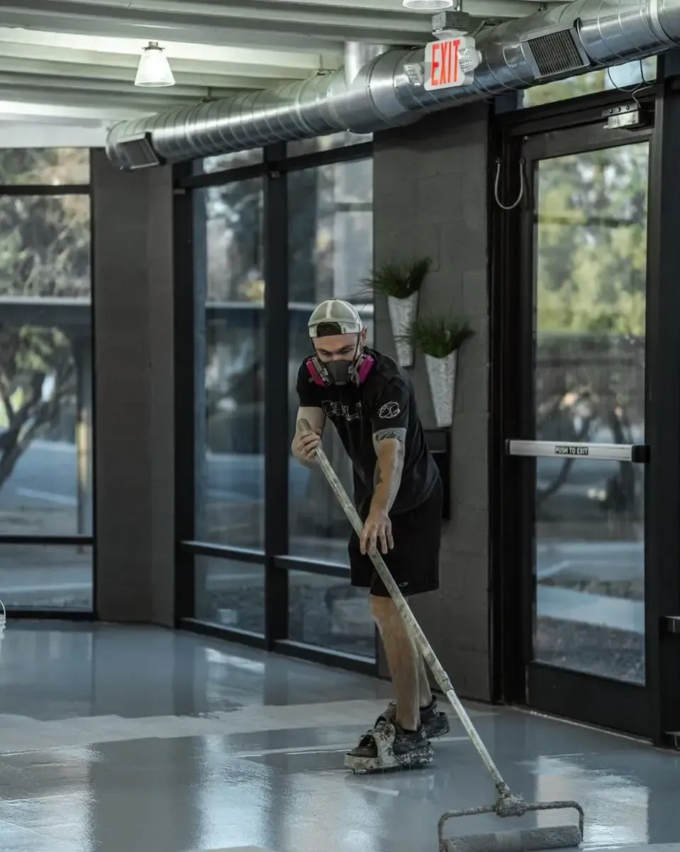 Professional installer rolling out an epoxy coating across a commercial concrete floor during application.