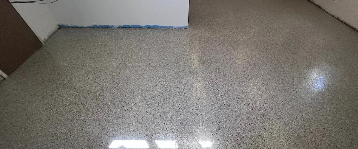 Freshly installed epoxy garage floor coating with flake texture and glossy finish under bright lighting.