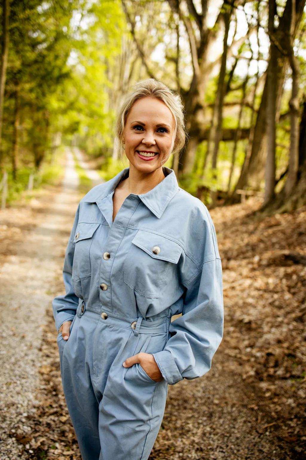 Shannon Renae Tomlinson smiling on a sunlit wooded path