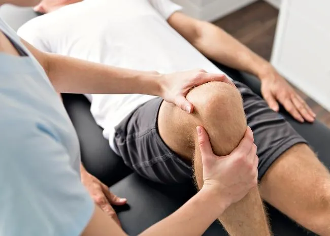 Therapist providing injury prevention and knee recovery treatment for athlete's knee