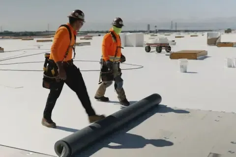 Woodbury Commercial Roofing crew walking large flat roof during TPO membrane installation