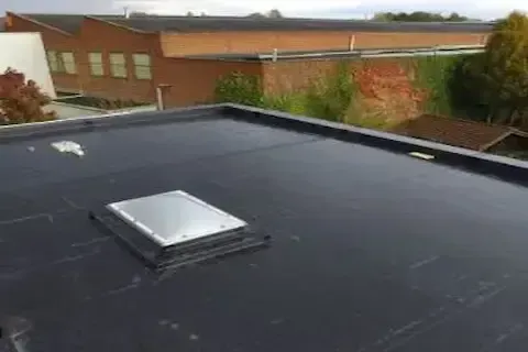 Completed EPDM flat roof installation with rooftop skylight on commercial property