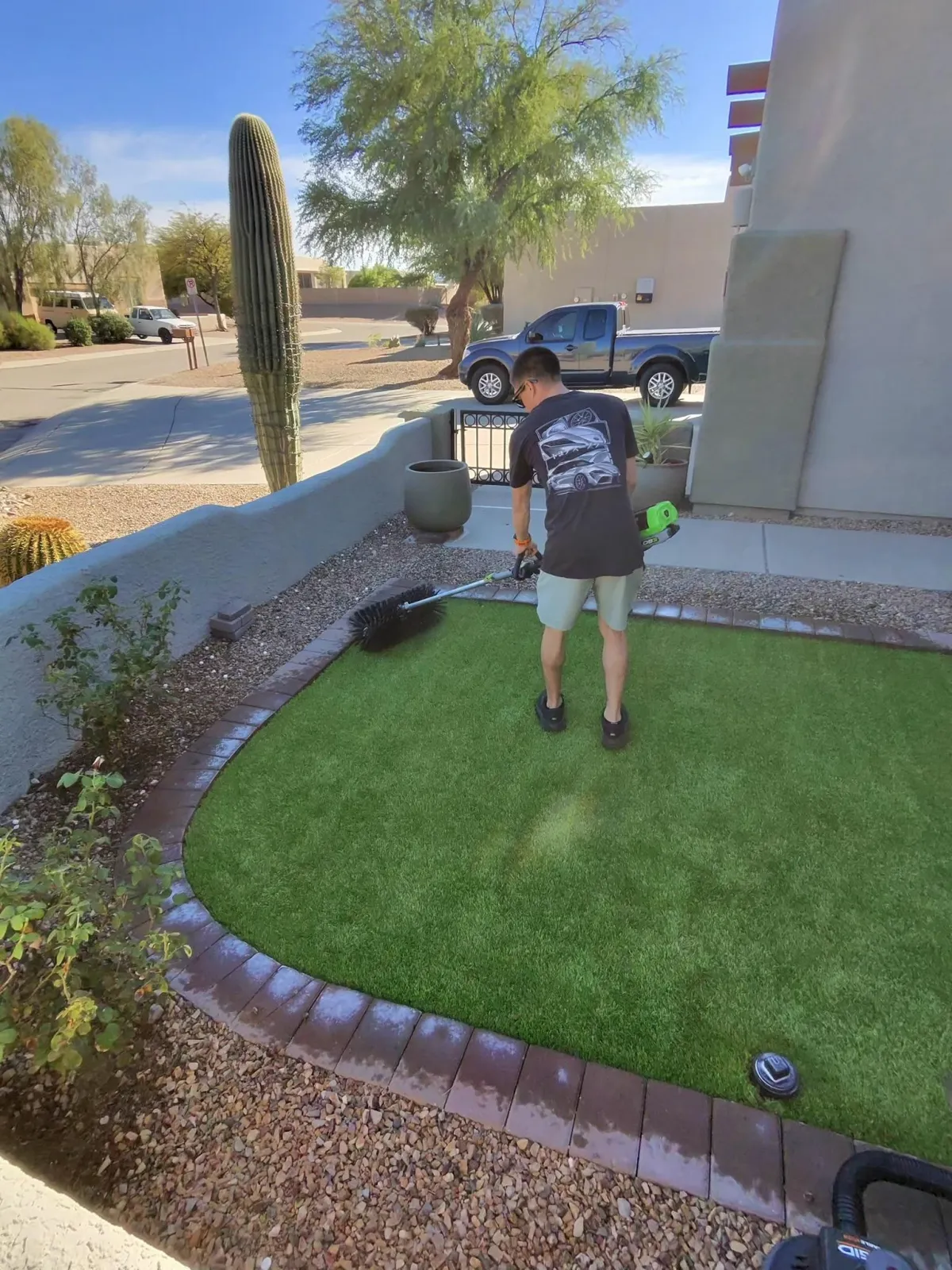 Professional Tucson turf cleaning technician restoring artificial grass with commercial equipment