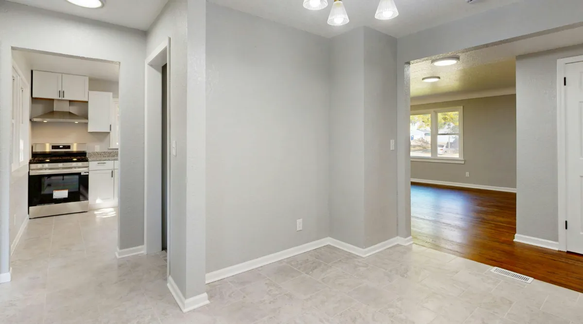Modern living room remodel featuring stone fireplace, neutral sectional sofa, accent chairs, and large sliding glass doors leading to a landscaped backyard