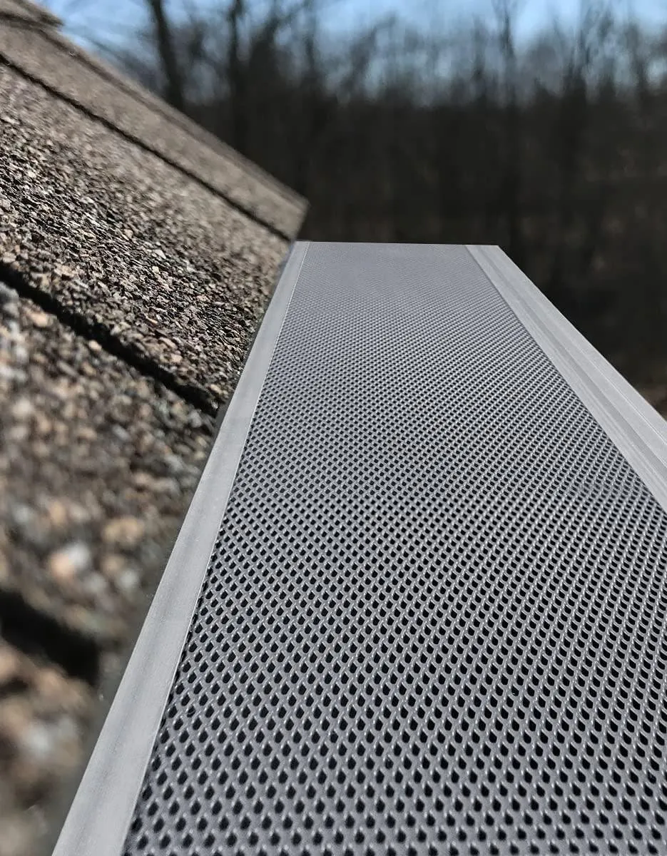 a newly installed gutter guard on a shingle roofing