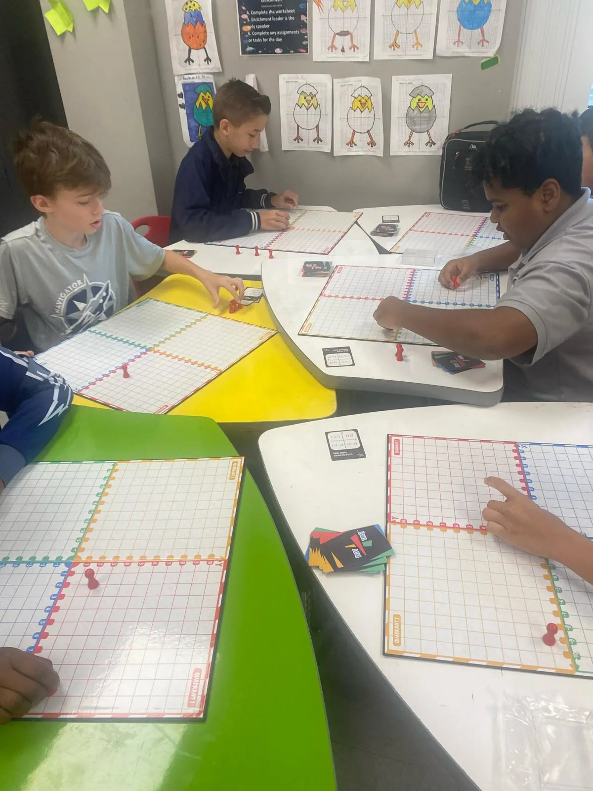 Students practicing graphing with manipulatives on coordinate‑plane boards