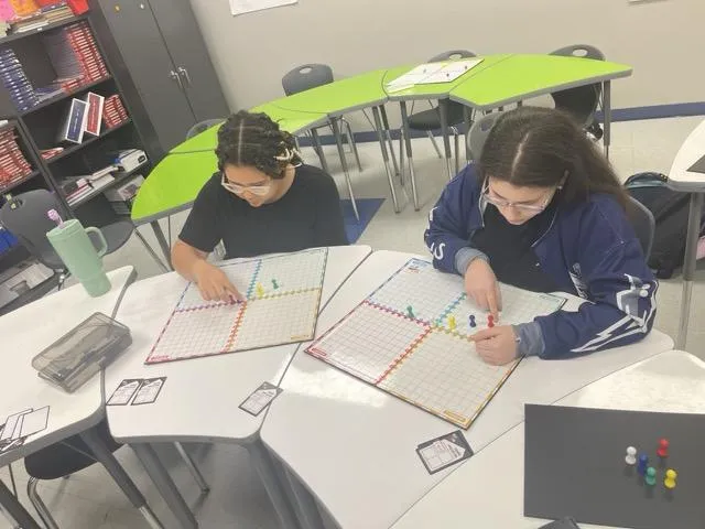 Two students plotting points on a coordinate‑plane game board