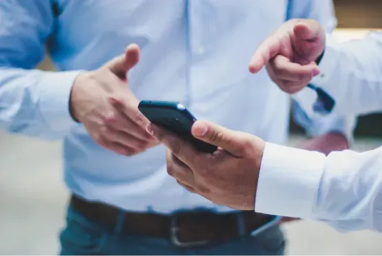 Two people in business attire discussing how to grow their small businss with Myracai.com using a smartphone