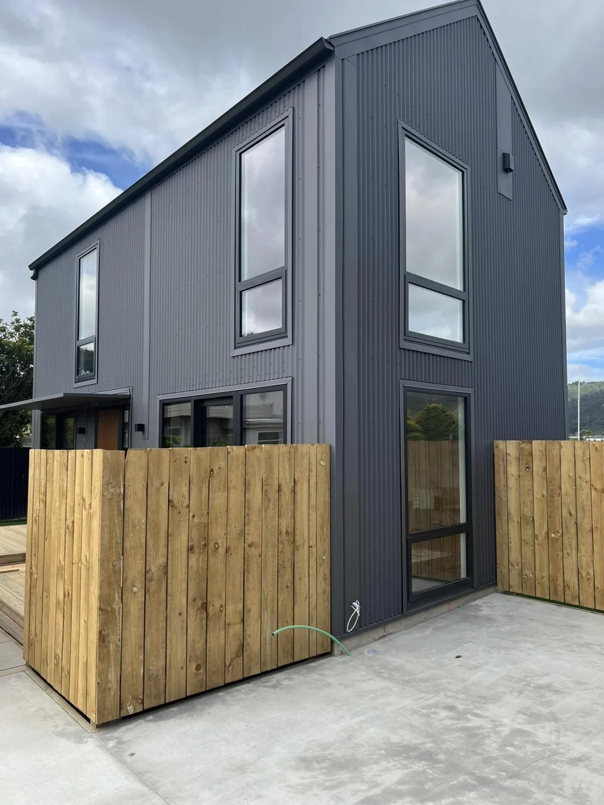 Black home with timber fence showcasing new roofing and cladding by Ultimate Roofing and Cladding
