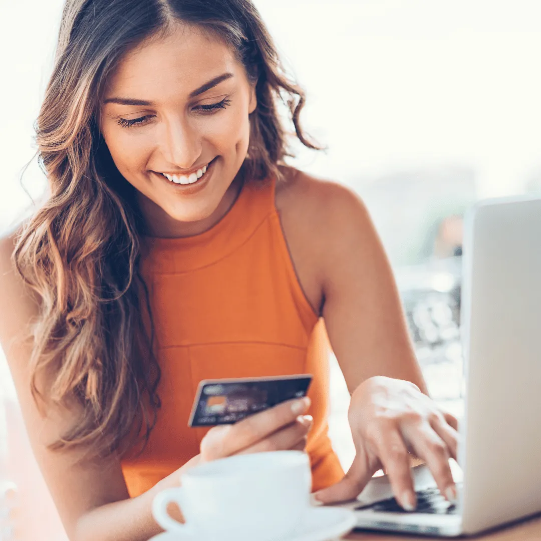 woman in an orange shirt making an online purchase with a creditcard