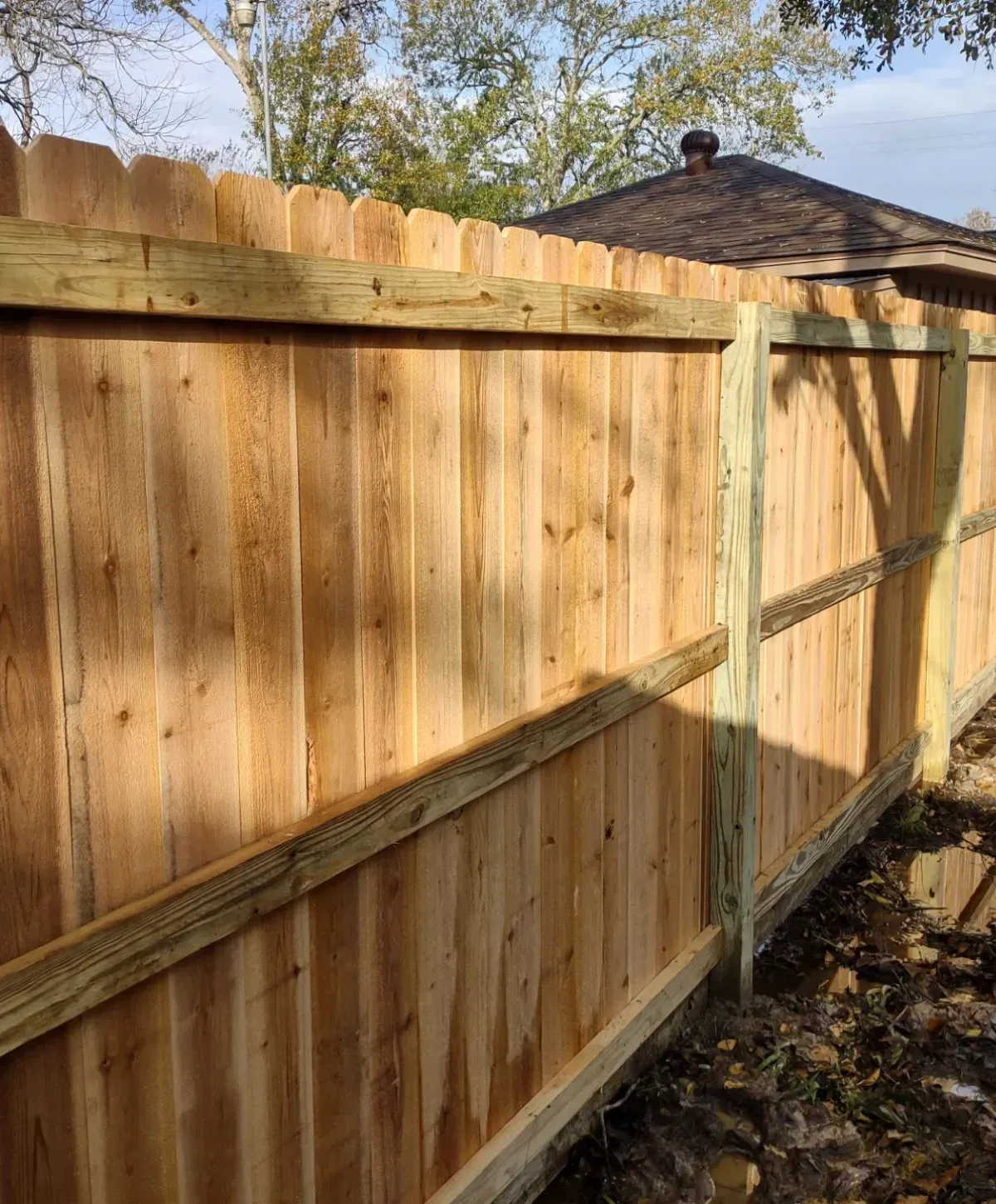 Newly installed wood privacy fence in College Station, TX, showing clean, straight lines and natural finish