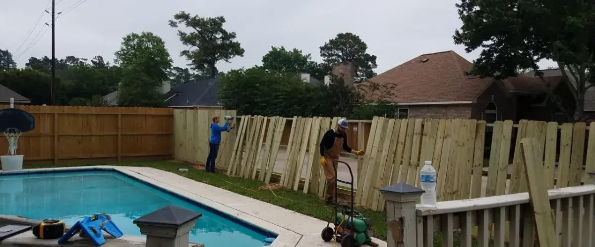 Wooden pool fence installation by contractors in backyard