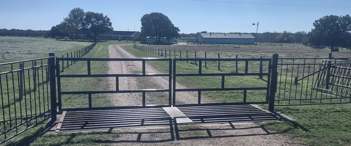 Ranch driveway with sturdy black metal gate installation in College Station